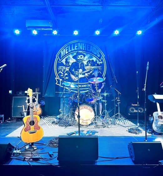 Mellenheads stage setup with drum kit and guitars under blue lights